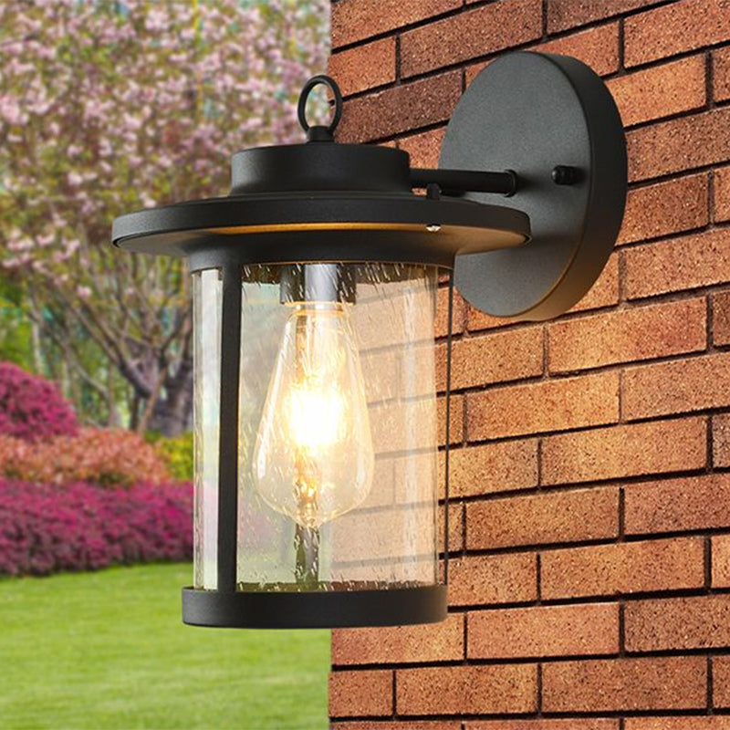 Cylinder Seeded Glass Wall Mounted Lamp Industrial Single Bulb Porch Sconce Light in Matte Black/Bronze with Cage Clearhalo 'Art deco wall lights' 'Cast Iron' 'Glass' 'Industrial wall lights' 'Industrial' 'Middle century wall lights' 'Modern' 'Rustic wall lights' 'Tiffany' 'Traditional wall lights' 'Wall Lamps & Sconces' 'Wall Lights' Lighting' 968922
